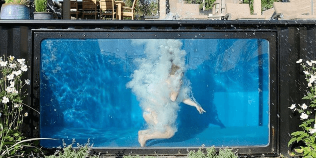 a person underneath the water of a shipping container pool