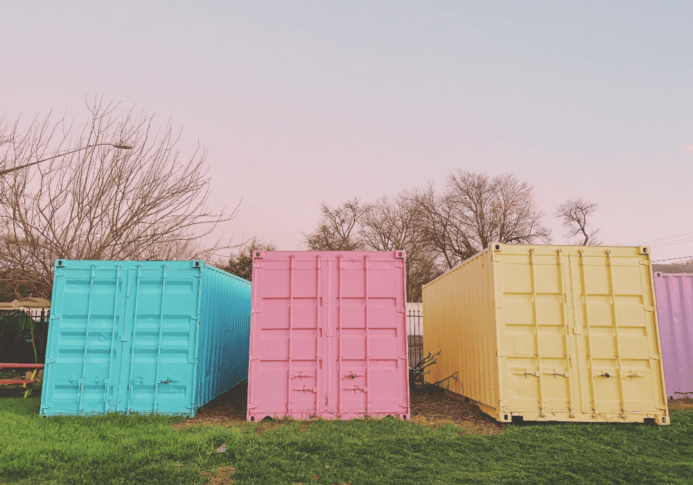bright colored shipping containers sitting on some grass.