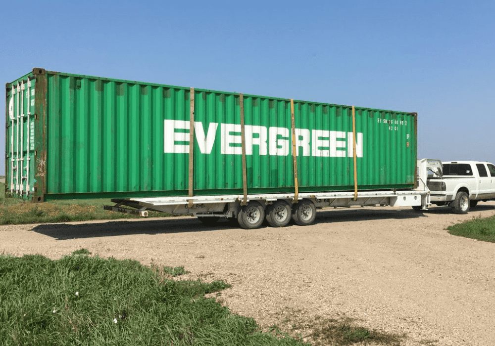 A large green shipping container on the back of a trailer.