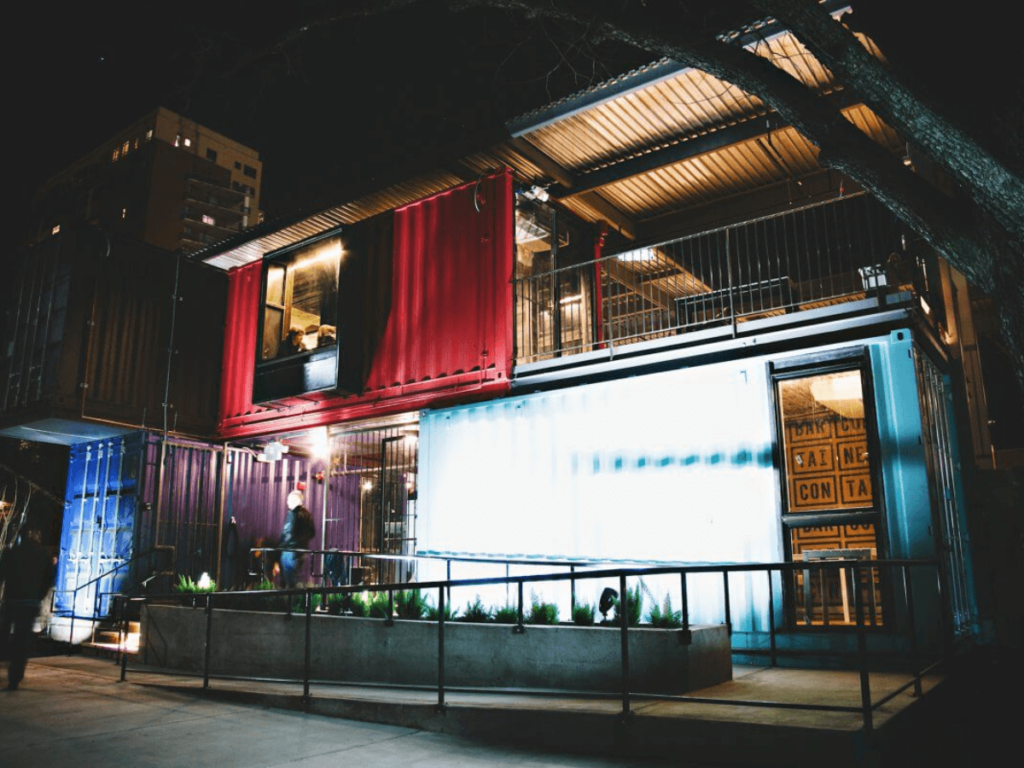 A shipping container restaurant lit up at night.