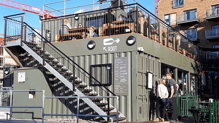 A shipping container restaurant/bar with seating on top. 