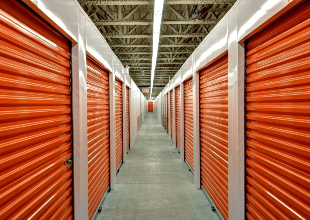 A long hallway lined with self-storage units with orange doors. 