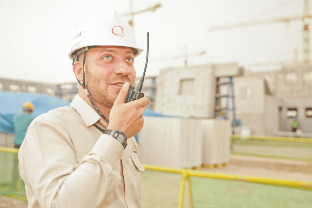 A man in a hard hat talking on a walkie talkie