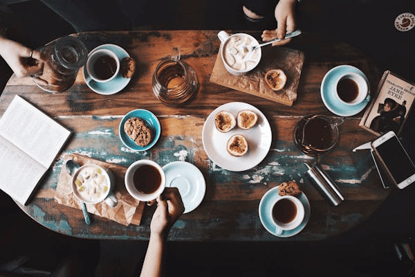 An above view of a dining table filled with food, cups, and plates.